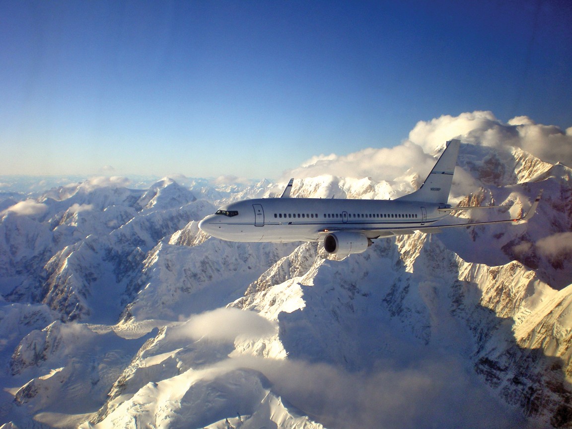 aircraft in flight with mountains and clouds in background