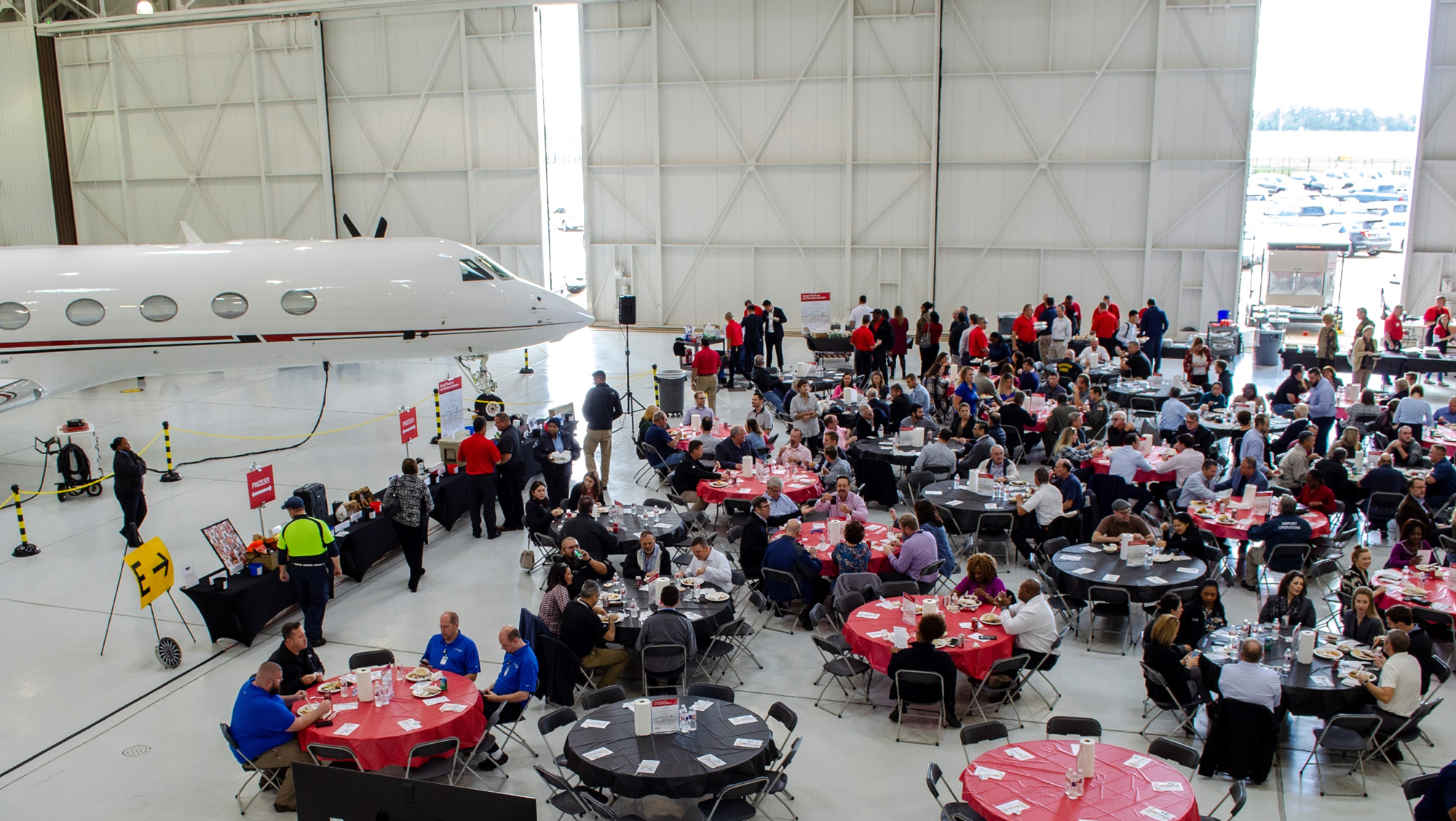 overhead view of hangar filled with round tables and people gathered